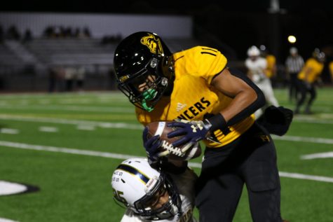 Sunny Hills wide receiver and defensive back senior Wilson Cal tucks the ball in while trying to avoid a tackle by a Sonora defender during the first quarter of the Oct. 4 homecoming game at Buena Park stadium. Cal later scored the game's first points on a touchdown reception at the corner of the end zone. Photo by Accolade photographer Paul Yasutake