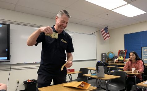 International Baccalaureate Economics HL1 teacher Robert Bradburn holds a $20 and $10 bill before putting the money into an envelope during the Oct. 18 ASB-sponsored