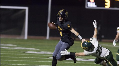 Quarterback senior Luke Duxbury pushes down a Notre Dame linebacker to avoid getting tackled in the first half. Duxbury threw two touchdowns in the first half of the 49-24 rout Nov. 15 of Notre Dame of Riverside at Buena Park High School stadium. Photo taken by Accolade photographer Paul Yasutake