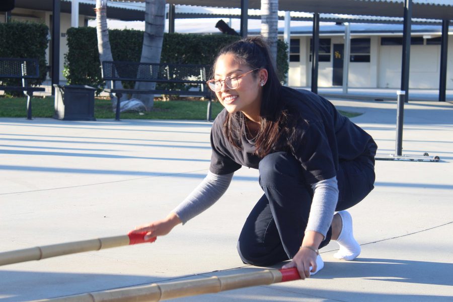 Accolade staff writer and Bayanihan Club member junior Gianne Veluz clicks the two 10-foot-long plastic bamboo sticks in one of her many practices to prepare for the Feb. 6 International Food Faire assembly. Photo taken by Accolade photographer Brianna Zafra.