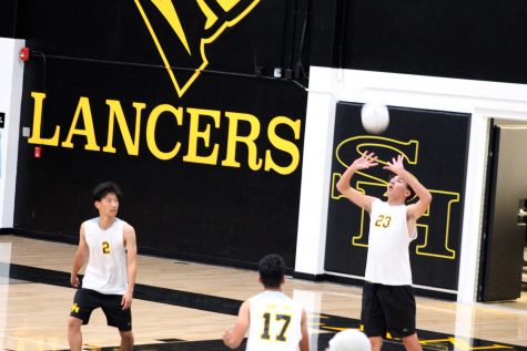 Junior Jason Thomson (right) passes the ball to a teammate during the Lancers' home opener loss to Crean Lutheran Feb. 25 in the Sunny Hills gym. Photo taken by Accolade photographer Brianna Zafra