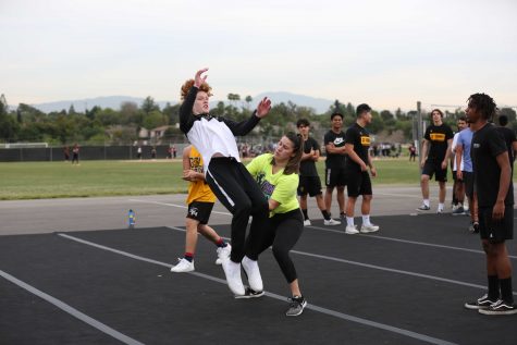 Cheer coach Lizzy Mejia (right) helps basketball player and male cheerleader sophomore Jacob Dedeaux perform a backflip as male cheerleaders watch in the background on the Sunny Hills blacktop during a Feb. 27 practice. Dedeaux and 18 other male athletes will show off their skills in the March 13 assembly. Photo taken by Accolade photographer Paul Yasutake