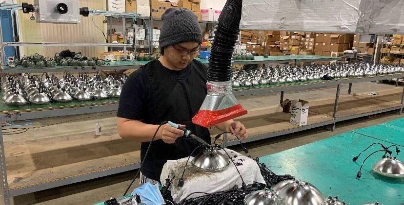 Senior Phillip Kim is shown hot gluing wires to headlights for commercial vehicles and airport signals under a fan to speed up the drying process. Image used with permission from Phillip Kim.