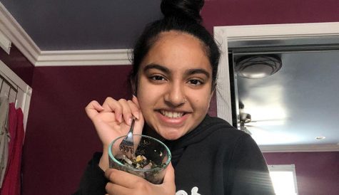 Nevya Patel uses her own smarthpone to capture her holding a bowl of spiced vegetables, including onions, spinach and corn and black beans, which she eats as her healthy snack. She incorporated the beans to make sure she is still receiving protein because of the lack of meat intake.