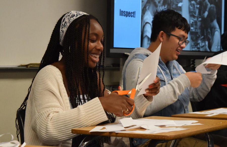 Then-junior Ella Eseigbe (center) cuts paper during a classroom simulation of a tent-making company in her IB Economics Higher Level 1 class last November. The class’ corresponding exam is just one of the many assessments that IB is modifying for the 2020-21 school year. 
