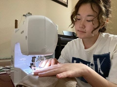 With her sewing machine, junior Violet Kim makes a denim bag for her first collection released Sept. 12. Kim is wearing a shirt from her collection as well.