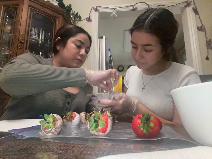 Sweet Treats DB owners junior Daniela Rosales (left) and junior Brianna Ruiz (right) make one of their specialty confectionaries, candy coated strawberries which go for $1 each. 