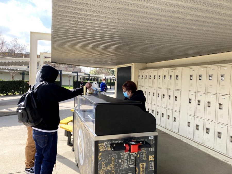 A student receives a free school breakfast meal during break beside the 70s and 90s building on Feb. 16, the first day of hybrid instruction since December 2020.