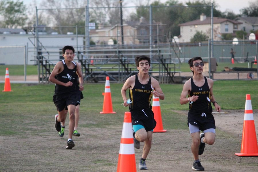 Masks in hand, twin brothers and cross country runners David (center) and Sergio Perez (right) race toward the finish line Feb. 3 on the Sunny Hills track, where the first sports event of the school year was held after the coronavirus pandemic had shut down all previous athletic competitions since last March. The Lancers boys cross country team -- the only SH squad with enough athletes in attendance to compete -- defeated the runners from Buena Park High School by a three-point margin.