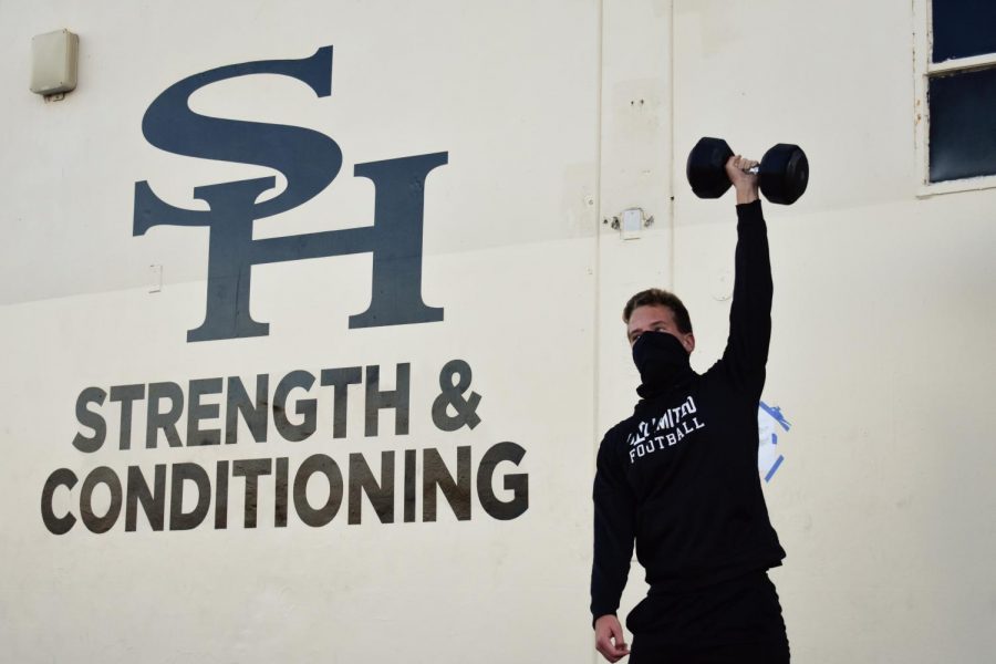 Tight end and linebacker freshman Connor Irons does a dumbbell shoulder press in front of the weight room during a Jan. 27 practice in preparation for the return of the football season, which will begin at a March 12 home opener against Fountain Valley.