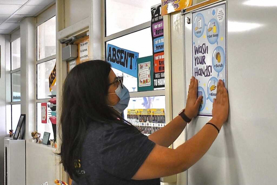 In preparation for the first day of school, math teacher Cristian Bueno posts a sign Aug. 13 to remind students of proper hand hygiene in Room 65. The poster, along with another one about indoor masking, was provided by the Fullerton Joint Union High School District as part of its health and safety guidelines for the 2021-2022 school year.