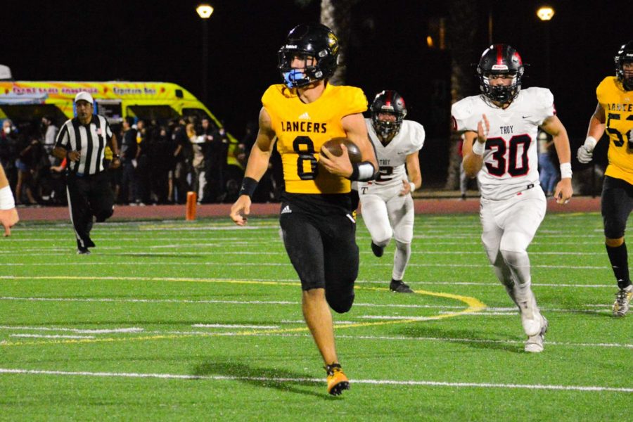 Quarterback+senior+Max+Spero+runs+to+avoid+getting+tackled+during+the+third+quarter+of+the+Oct.+15+game+against+the+Troy+Warriors+at+Buena+Park+High+School+Stadium.+The+Lancers%2C+who+were+playing+in+their+homecoming+game%2C+came+away+with+a+22-20+win+that+had+all+the+makings+of+a+rivalry+affair%2C+especially+in+a+wild+two+minutes.