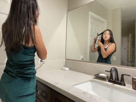 In her deep forest green colored dress, senior Minjeong Kim practices curling her hair in front of the mirror before attending the Homecoming dance on Oct. 16 at the Sunny Hills High School quad.