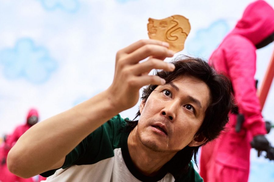 Gi Hun (Lee Jung Jae, “Along with the Gods”) brings his dalgona, a honeycomb-like candy, to the light, and discovers a new way to cut out the umbrella shape during ppopgi, the second round of the competition that comprises “Squid Game.”