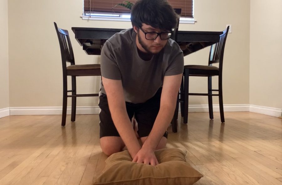 Senior Elijah Ramirez demonstrates CPR chest compressions on a pillow on Sept. 30  in his dining room as a replacement for a dummy or a stuffed animal. Ramirez had to video record himself practicing hands-on CPR and submit a video for review/approval by assistant principal Hilda Arredondo to fulfill a state-mandated graduation requirement.