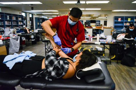 Senior Aute Blackwell holds her right arm up while an American Red Cross nurse preps it before the blood draw during the Thursday, April 21, blood drive in the Lyceum.