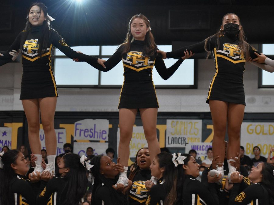 Cheerleaders (left to right) senior Alysa Lee, junior Alyssa Rhee and sophomore Aly Chow perform a half stunt during their routine at the beginning of the year assembly Aug. 19 in the gym during first period. 