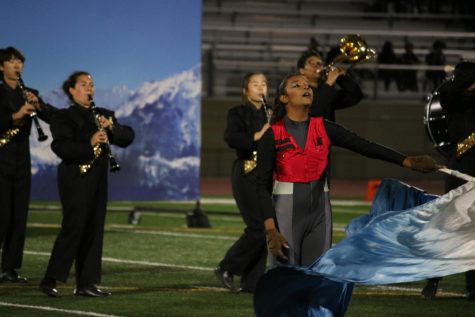 Color Guard member sophomore Janessa Lima (center) swings her flag while other members of the Lancer Regiment behind her play their instruments during “The Summit” performance Saturday, Nov. 19, at Bolsa Grande High School.