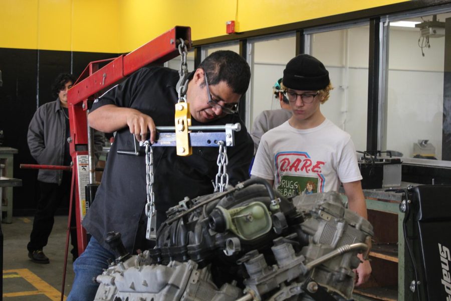 New auto shop teacher Jesse Munoz (left) demonstrates how to fabricate an engine support brace to sophomore Jacob Carr in his Advanced and Intermediate Auto Shop second period class in Room 131 last semester. 