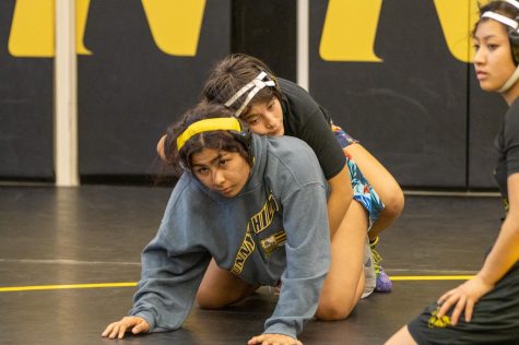 Senior Kayla Alamos (above) puts her left arm around senior Kylie Yang to demonstrate the referees position during wrestling practice on Wednesday Nov. 16, in Room 153.