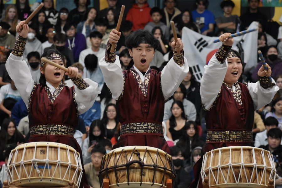 Korean Culture Club [KCC] members junior Karen Kim (left), seniors Brandon Lee and Clara Kim end their nanta, a coordinated group drum show, during the International Week assembly in the gym on Friday, Feb. 10.