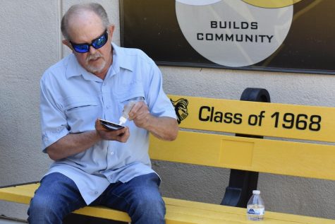 Class of 1968 reunion committee member Jim Gronwall adds glue Thursday, March 9, to the inspirational message plaque that will be attached to the center of the black and yellow bench underneath the “Class of 1968” engraving. The bench in front of the library and the plaque are among the nearly $10,000 in outdoor furniture that school officials purchased using money raised by the ‘68 reunion group.