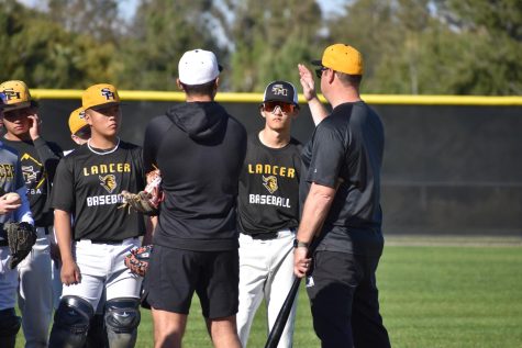 First-year baseball head coach Christopher Vogt (right) teaches his players how to properly throw a ball during an afterschool practice Monday, March 2.