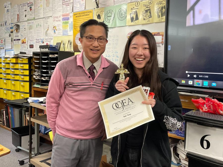 The Accolade editor-in-chief senior Kate Yang (right) holds her first-place newspaper layout trophy and certificate Monday, March 6, after adviser Tommy Li shows a video clip announcing Yang as the winner from the Saturday, March 4, awards ceremony. (Image taken by Sheila Neri.)