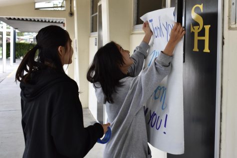 Associated Student Body [ASB] members juniors Prysilla Ahn and Hannah Garcia tape up a poster for social science teacher Hera Kwon on the door of Room 52 during third period on Thursday, May 11, for Teacher Appreciation Week. The poster says, “Thank you Mrs. Kwon, We Love You!”