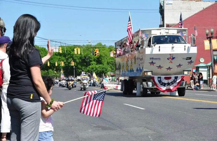 Then-4-year-old sophomore Paige Bringas stands with her mom, waving the flag toward an arriving military vehicle during a 2010 Memorial Day parade. 