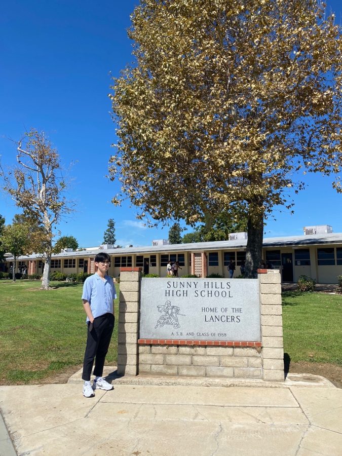 A GLIMPSE OF A NEW LIFE: Junior Daniel Kim stands in front of the Sunny Hills sign commemorating his new new school Sept. 23, 2022.
