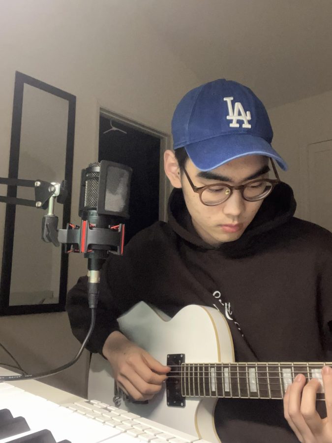 Austrian transfer student junior Daniel Kim strums a chord on his guitar while producing another song in his bedroom April 19.