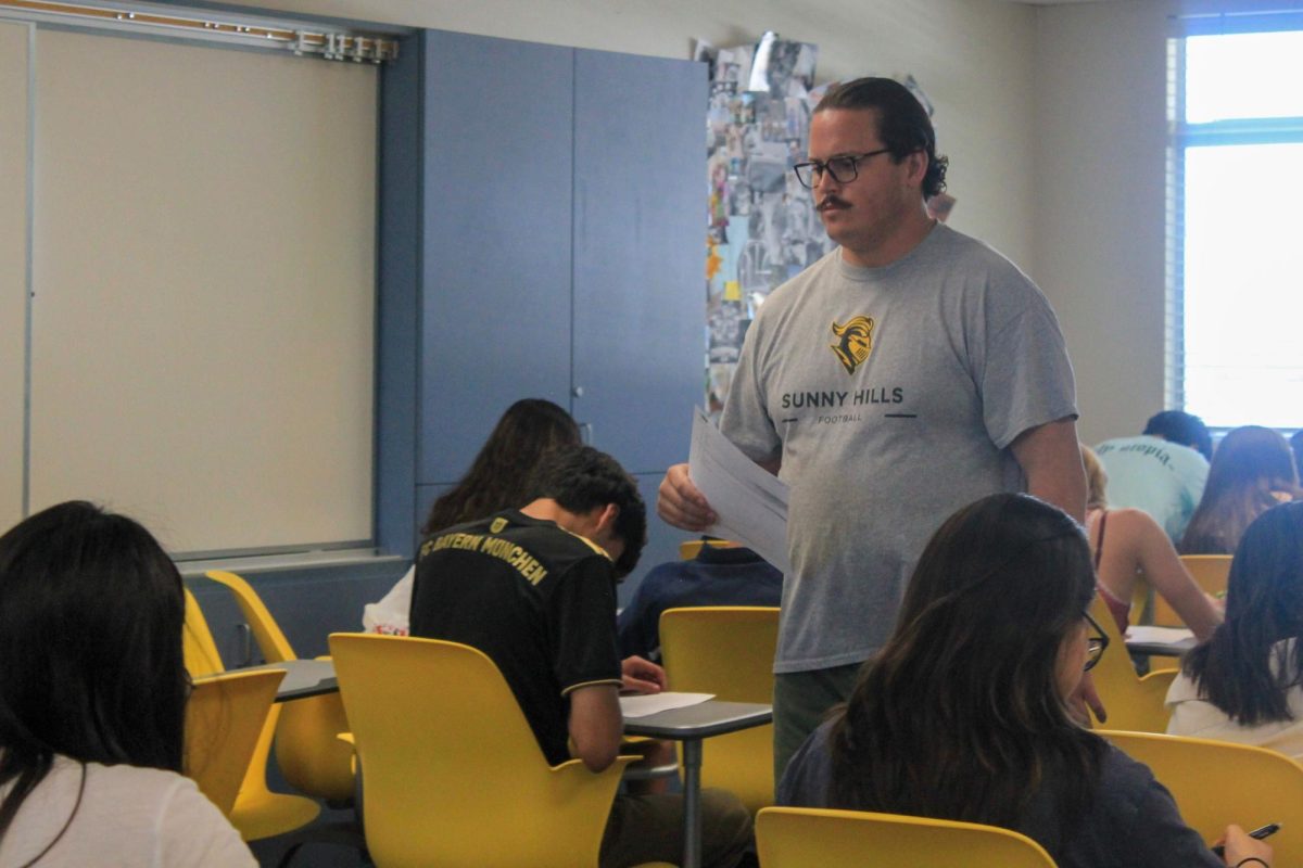 New social studies teacher Christopher Collodel monitors his students taking an Advanced Placement [AP] United States History quiz while delivering a test paper to a student on Friday, Aug. 25, in Room 184. 
