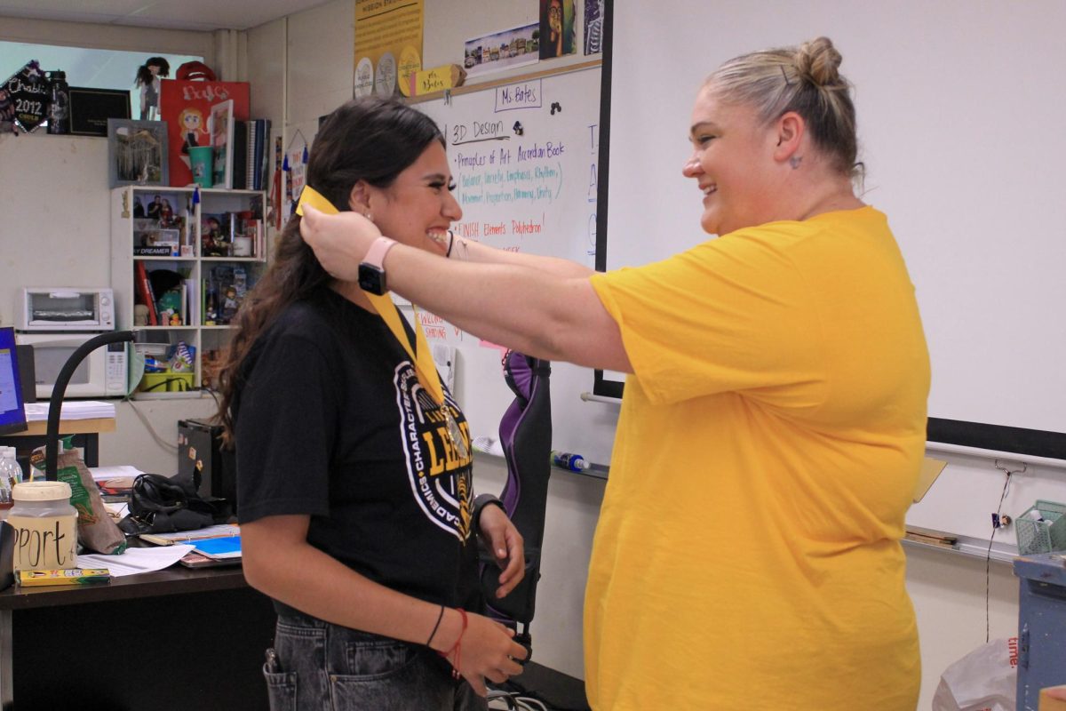 Art teacher Chablis Bates awards senior Camila Carriedo (left) with the Lancer LEGEND medallion to recognize her act of selflessness on Sept. 1 in Room 22. 