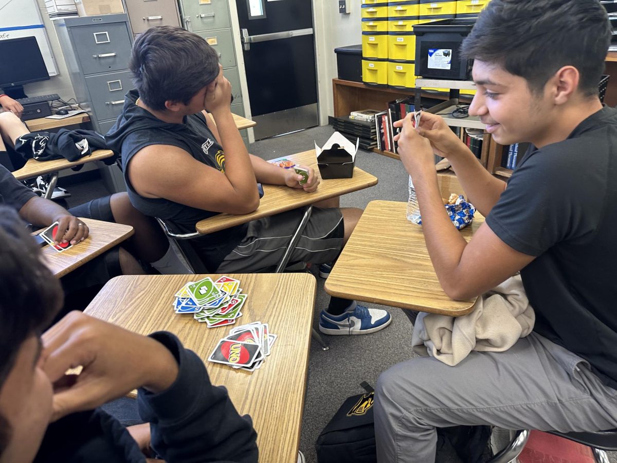 Sophomore Isaac Gaxiola (right) takes a look at the top of the Uno card stack during his lunchtime game with his friends Monday, Oct. 30, in Room 138. The group has recently been spending the second half of the 30-minute lunch period playing what an online article calls Americas Favorite Game. 