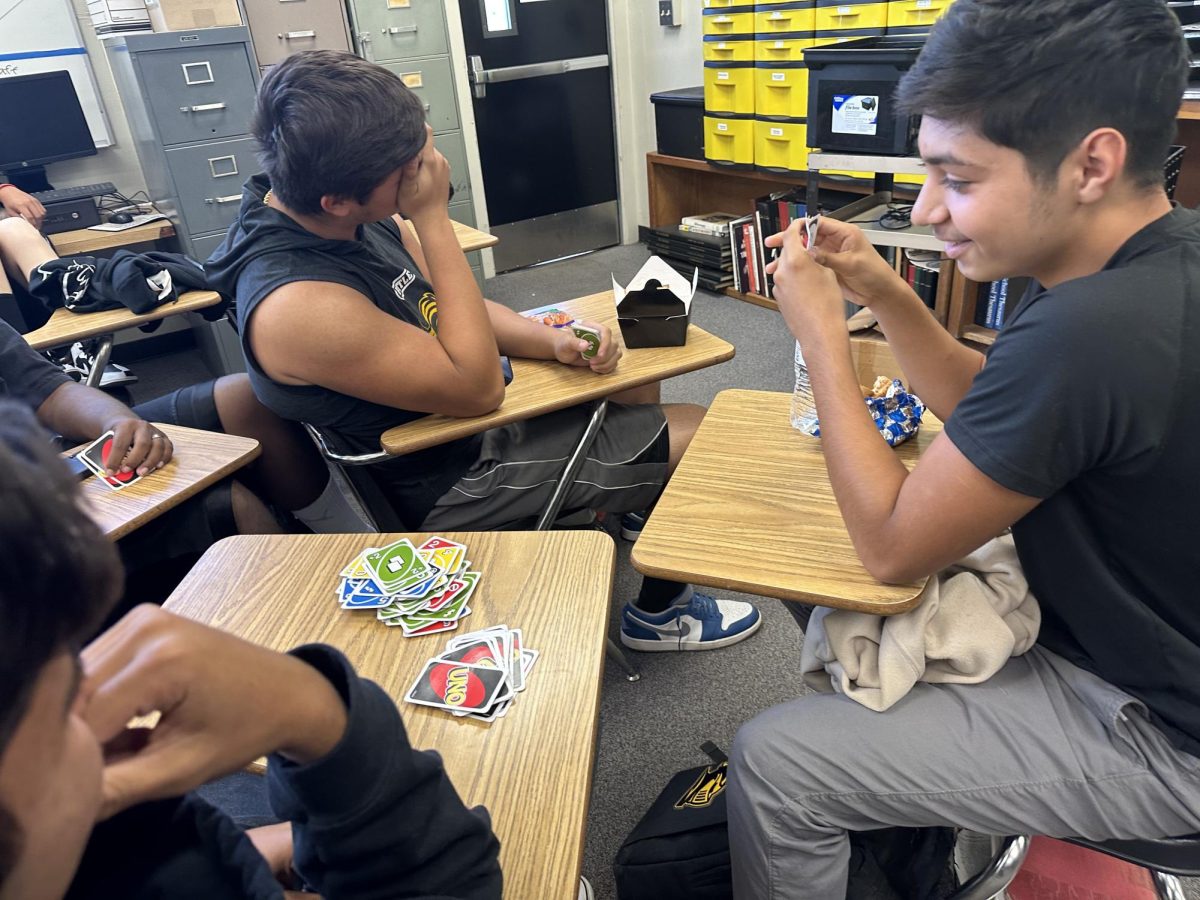 Sophomore Isaac Gaxiola (right) takes a look at the top of the Uno card stack during his lunchtime game with his friends Monday, Oct. 30, in Room 138. The group has recently been spending the second half of the 30-minute lunch period playing what an online article calls "America's Favorite Game." 