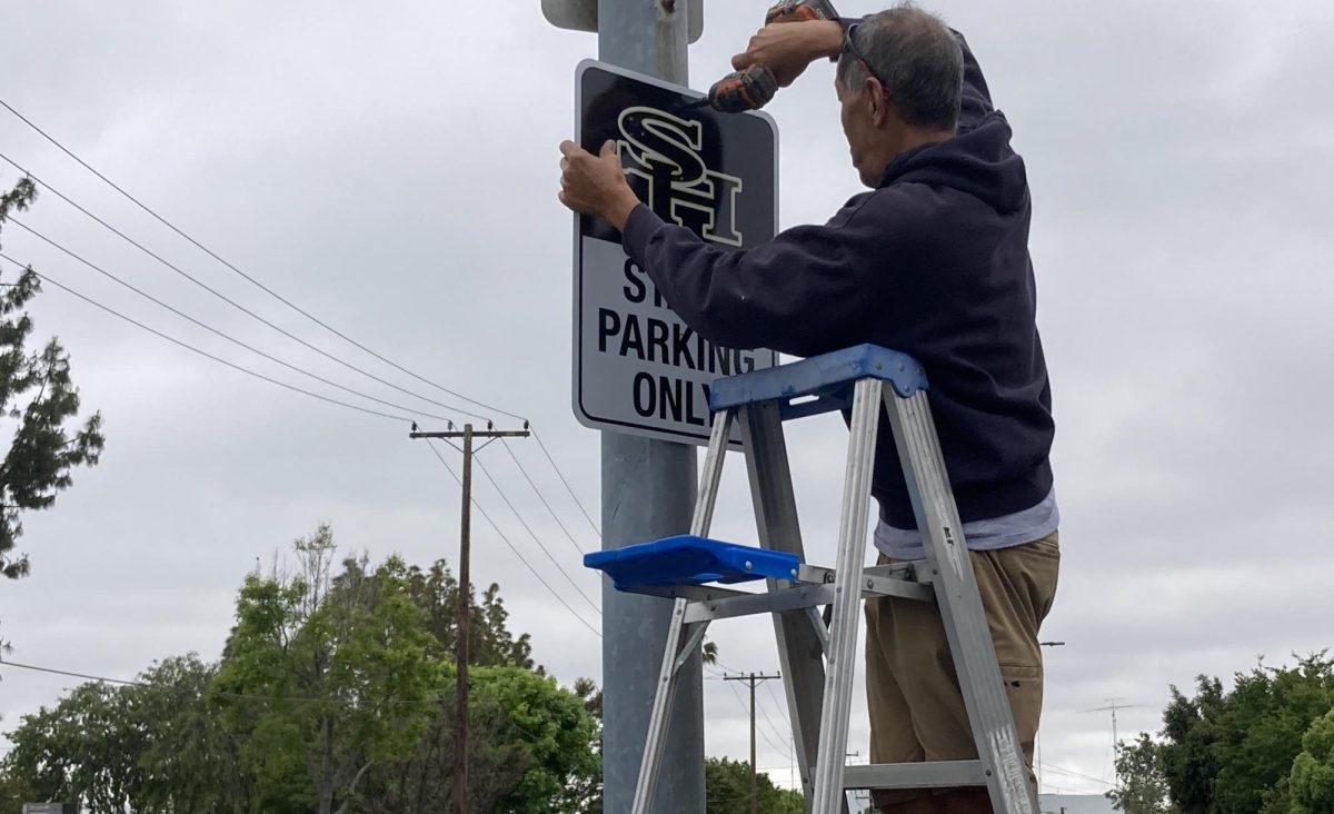 A worker from the Fullerton Joint Union High School District installs one of the many new staff parking signs featuring the “SH” logo on poles in the campus west parking lot. The signs — measuring 18 inches wide and 24 inches high — were put up at the end of May before finals week of the spring semester. School officials wanted them bigger to improve visibility since the previous ones measured only a foot wide and 18 inches high.
