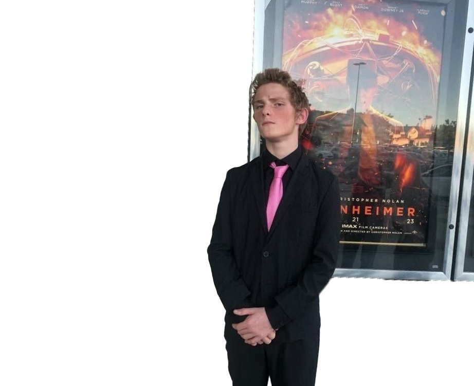 Sophomore Edward Galvez poses in front of the “Oppenheimer” poster at the AMC theater in Los Angeles on Saturday, July 25.