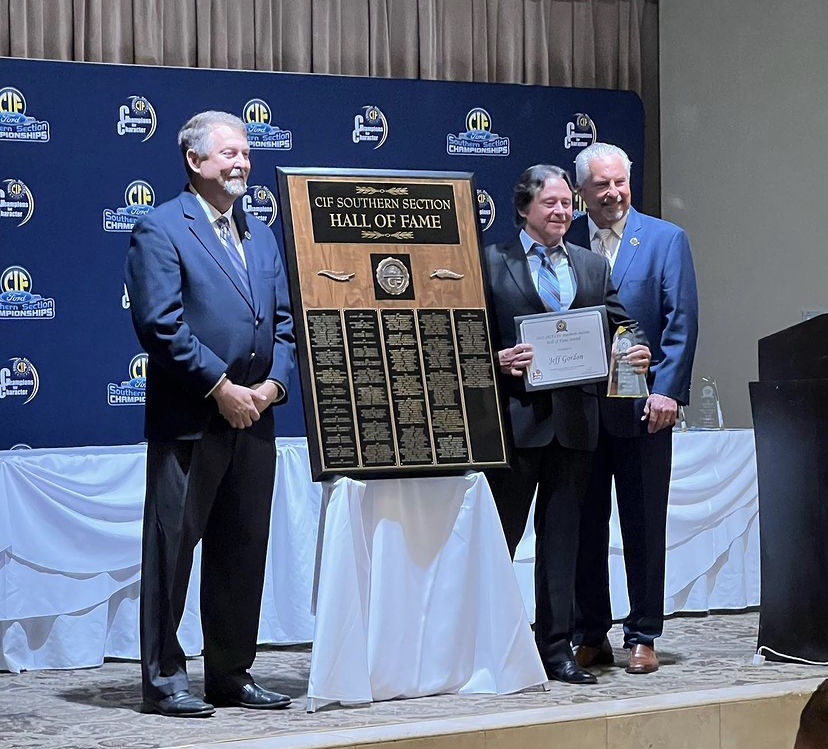 Former girls varsity soccer coach Jeff Gordon (center) holds a glass trophy and a certificate as part of his induction into the CIF Hall of Fame on Wednesday, Oct. 18, at The Grand’s Conference Center Ballroom in Long Beach. To Gordon’s left stands a plaque that  contains the names of past and present Hall of Fame inductees.