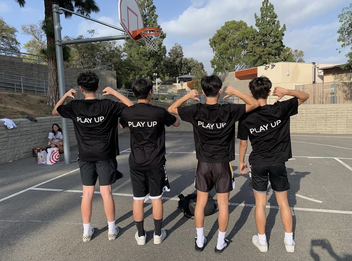 PlayUp coaches seniors Brandon Kim (left), Caleb Park, Justin Chung and Logan Kim show off their PlayUp merchandise at Parks Junior High School during a practice session on Thursday, July 6. 