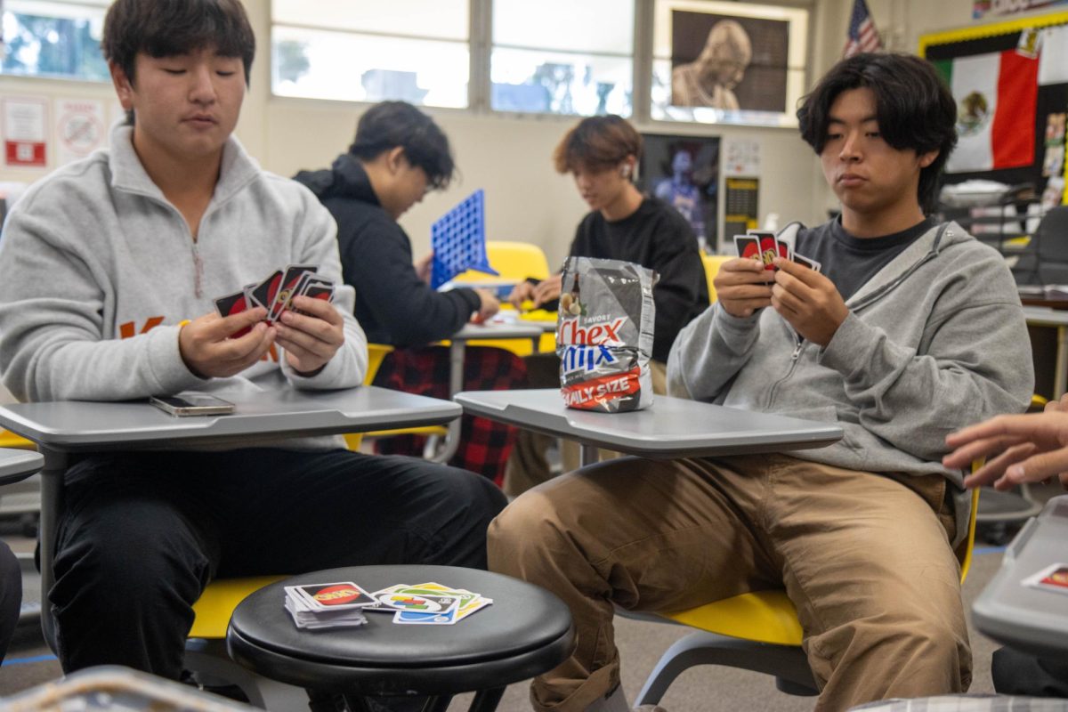 Juniors Dylan Lee (left) and Brian Kim play a game of UNO during a Board Game Club lunch meeting in Room 71 on Friday, Dec. 8. (Image taken by Noah Lee)