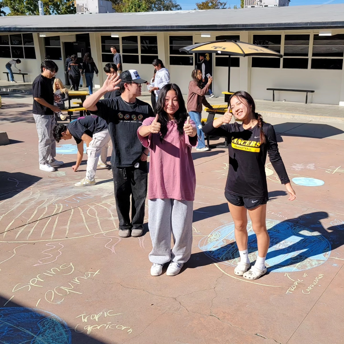  Juniors Olivia Ko (center) and Euree Kim stand near their chalk drawings during fourth period in Advanced Placement Environmental Sciences teacher Wesley Fairall’s class between the 80s and 100s buildings on Tuesday, Nov. 14, when the network outage first hit districtwide. While the class usually works digitally, Fairall adjusted to the lack of internet access with the activity.
