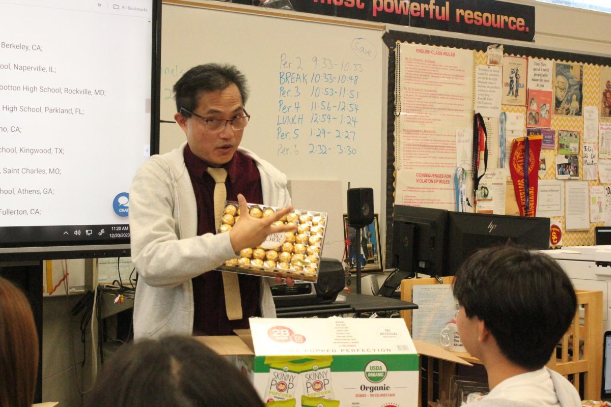 To celebrate the Columbia Scholastic Press Association’s Crown finalist nomination, The Accolade adviser Tommy Li presents a plastic container of Ferrero Rocher chocolates as a treat for staff members during the fourth period Advanced Journalism class on Wednesday, Dec. 20. Li wanted those on staff to know that regardless of any national award The Accolade will receive on Friday, March 15, he sees them as Gold Crown winners.