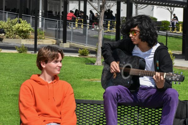 Junior Evan Sereg (left) listens to senior Nicolas Galven play his guitar during lunch in the quad on Thursday, March 7. 
