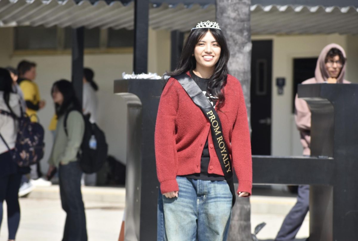Upon receiving a plastic tiara and a black sash, senior Seannea Arceo stands in the quad after being crowned to join the prom court during break on Thursday, March 28. 