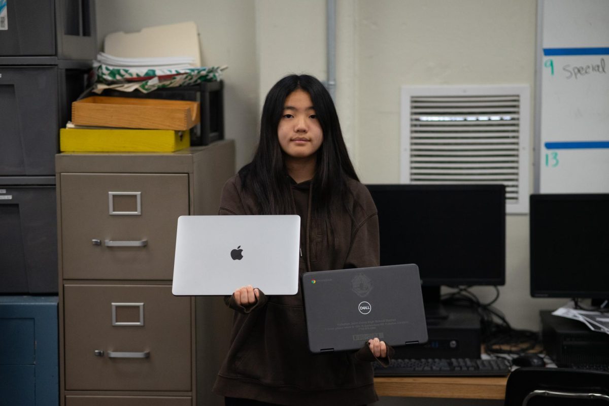 Freshman Kyuwon Han holds her MacBook in her right hand and Chromebook in her left hand in Room 138, Monday, May 13. Han holds her MacBook higher to symbolize her reliance on the device.