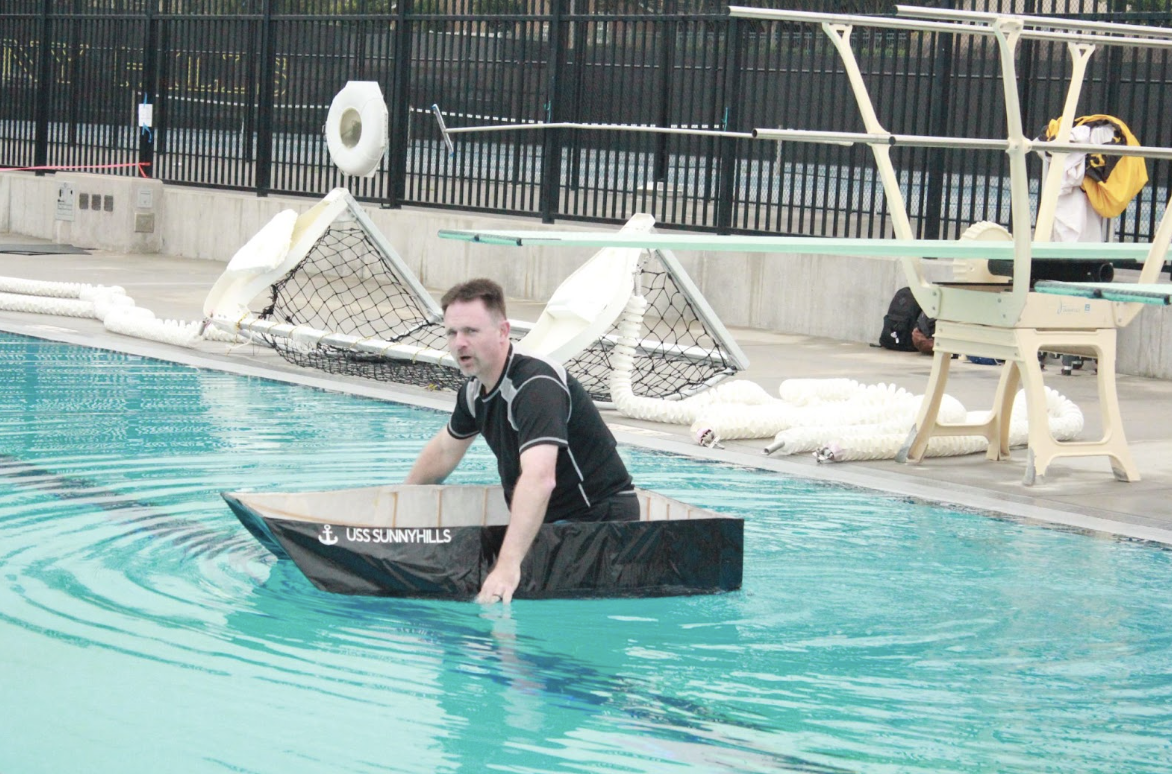 Principal Craig Weinreich attempts to make it across the Sunny Hills swimming pool in a boat while students from various classes watch during first period on Monday, May 20. The annual event features end-of-the-year projects in which Physics 1 and 2 students build boats made of wood sticks, glue, paper and paint. Those who make it all the way from one end of the pool to the other with an administrator or teacher on board will receive extra credit.