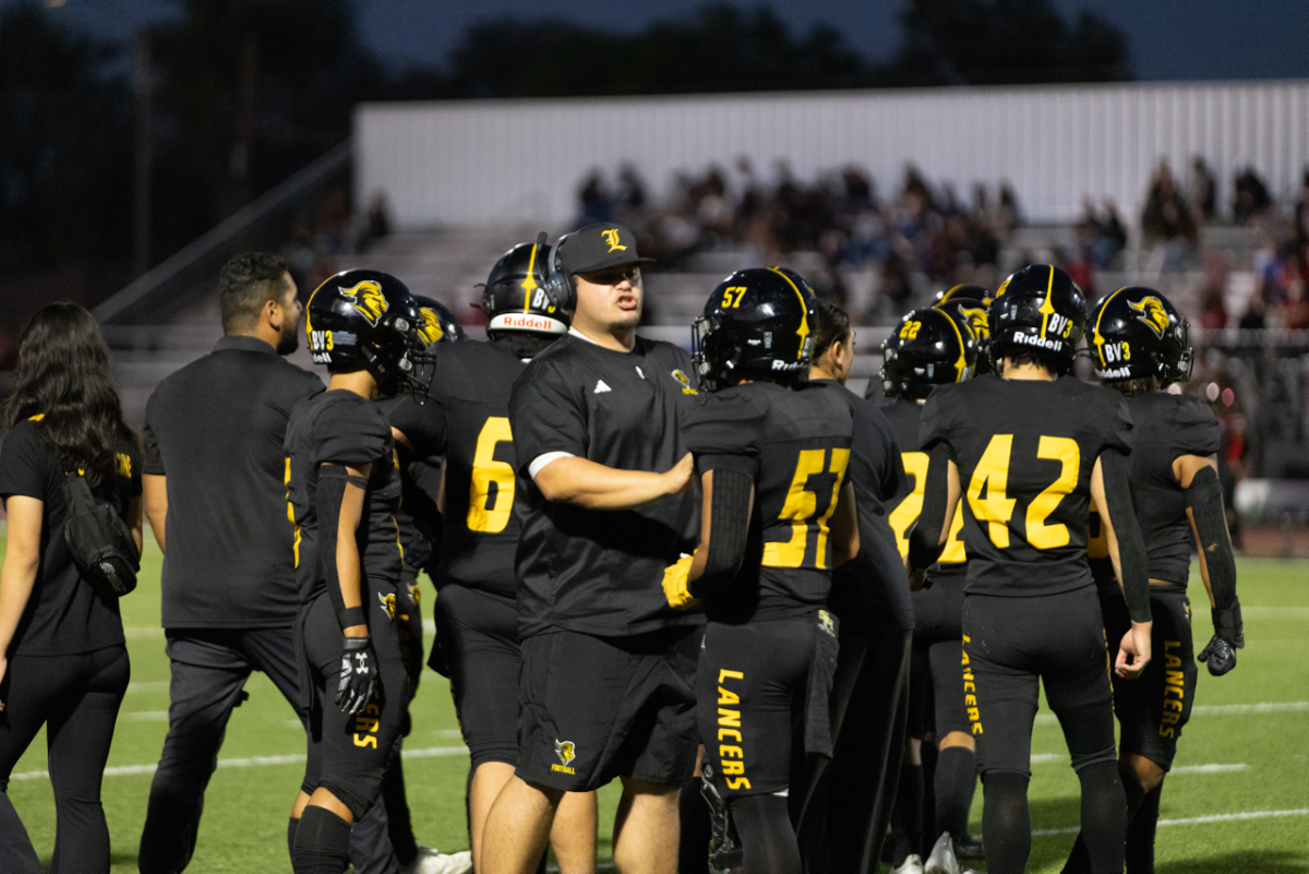 Assistant coach Chris Parrales (center) pulls aside offensive and defensive lineman senior Fenix Kawin after the Troy Warriors scored in the first football game on Friday, Aug. 23, at Buena Park High School stadium.