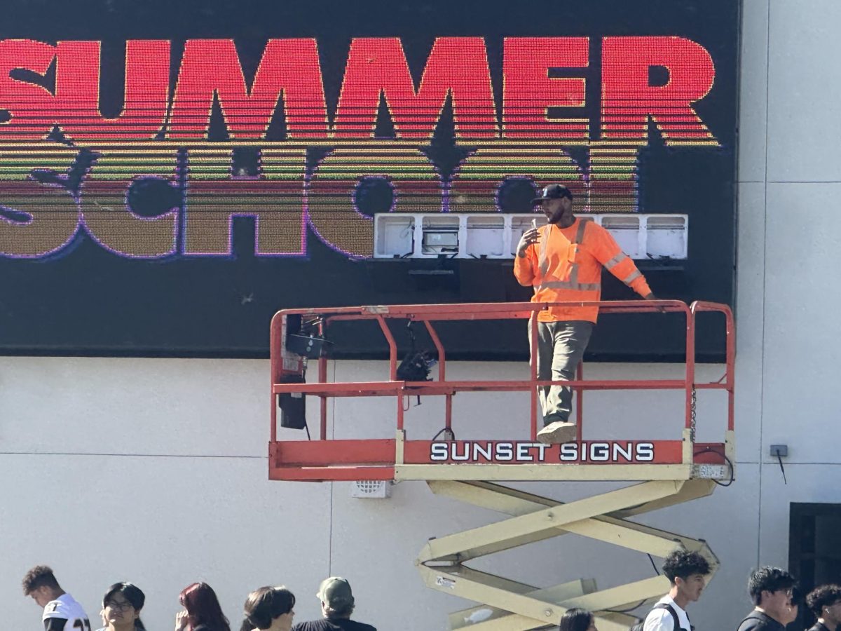 A technician stands on a lift as he prepares to repair certain tiles of the jumbotron in the quad during the passing period between first and second periods on Thursday, Aug. 22. The big screen, which shows “SUMMER SCHOOL,” has not been working since the start of the fall semester but resumed its normal display after the fix.