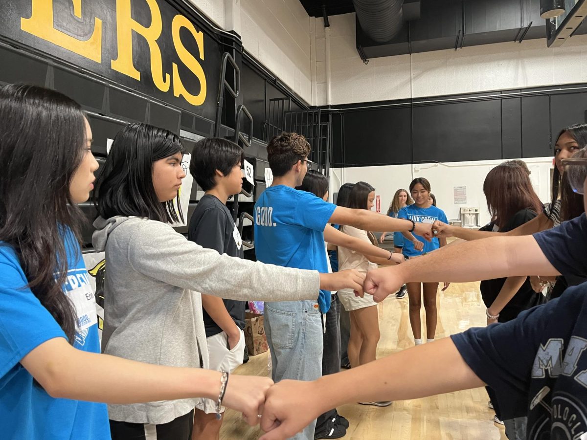 A mix of Link Crew leaders and the Class of 2028 freshmen line up facing each other, touching their fists to identify their partners on Wednesday, July 31, during Link Crew’s annual freshman orientation in the gym. The group, which works throughout the school year to ease ninth-graders’ adjustment to the high school climate, conducts this activity in the beginning segment of its orientation to get students active and comfortable meeting each other. 